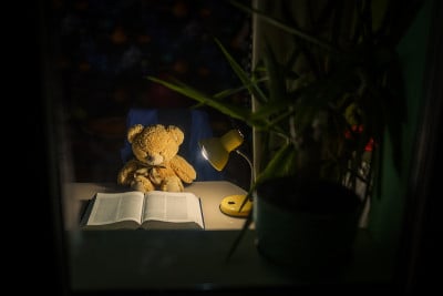 泰迪熊在房间里用夜灯看书