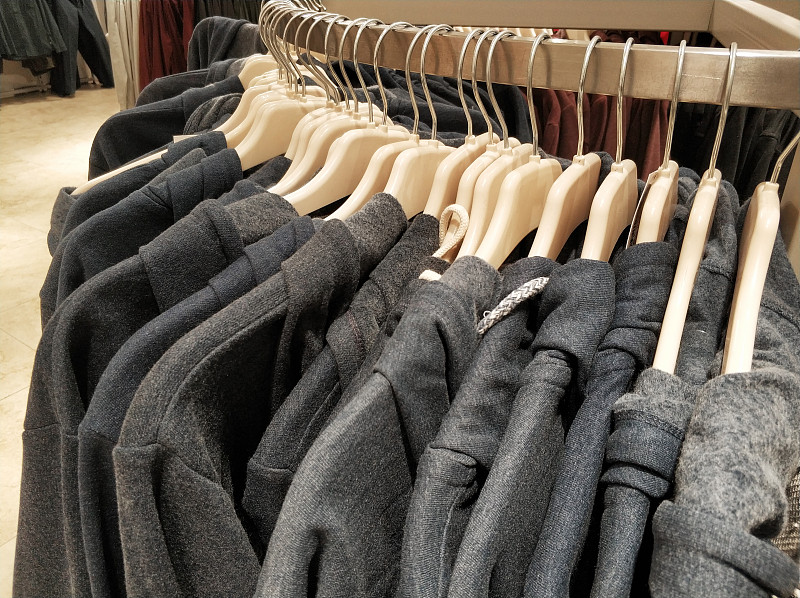 在服装店挂衣服，夹克和帽衫