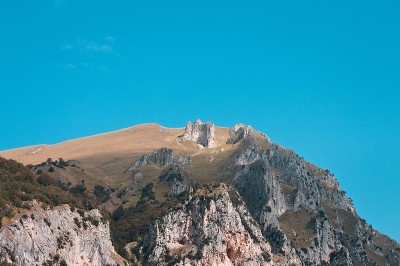 一束光照亮了布满岩石的山顶，绿色的草地(意大利马尔凯的西比里尼国家公园)