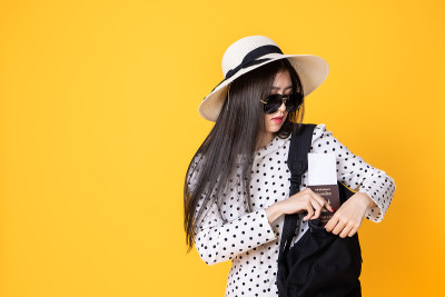 夏日休闲装的女游客。亚洲微笑女子。以黄色为背景出国旅行的乘客。一个亚洲女人要去度暑假。旅行有趣的旅行