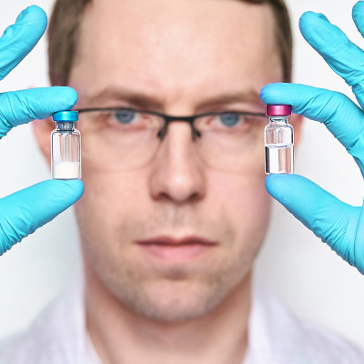 Person in gloves hold two vaccine bottles