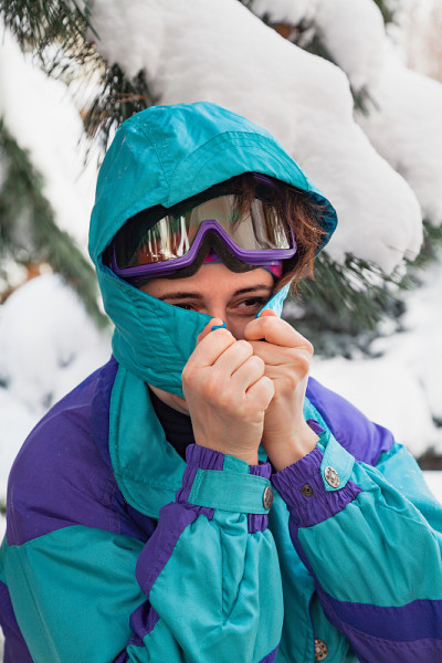 穿着滑雪服的女孩站在高大的松树下