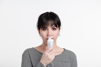 头像的黑发女人使用鼻吸入器。病人吸入药物