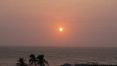 清澈的天空中，橙色的太阳照耀着大海，温暖而平静的夕阳照耀着海滩