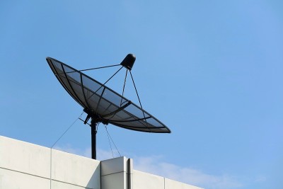 在蓝天背景下的建筑物屋顶上的卫星天线。