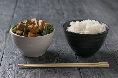 木桌上放着一碗米饭和一碗炸豆腐芝士。