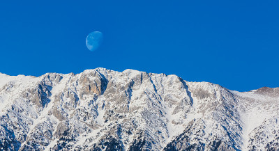 冬天的风景在山上，有白雪覆盖的山峰和落日的月亮