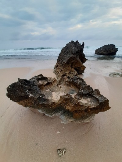 在小坂蓝海和云天的映衬下，沙滩上的单个岩石