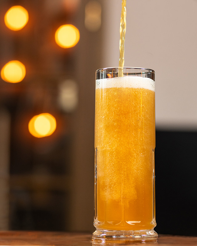 啤酒倒，倒到马克杯，玻璃与散景背景