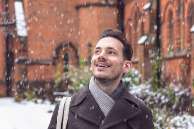 一个快乐的微笑的男人惊讶于冬天飘落的雪