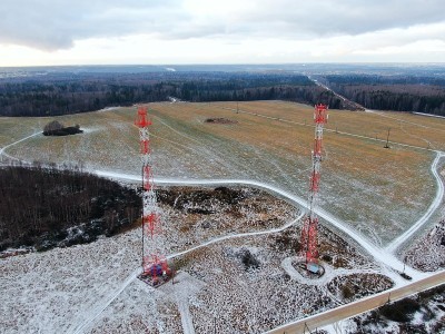 鸟瞰图电信塔的移动通信背景上的绿色田野覆盖着皑皑白雪。