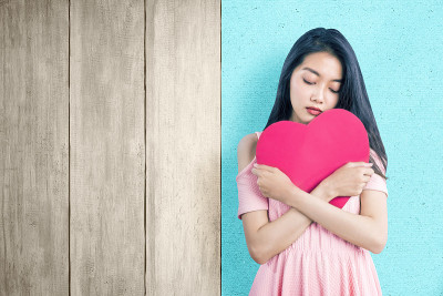 亚洲女人拿着一个红色的心与悲伤的表情