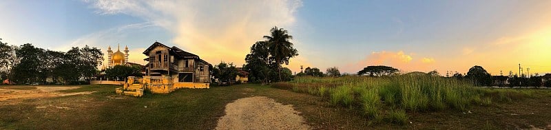 废弃的传统马来房屋，背景是清真寺