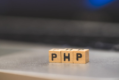PHP编程网络语言:字母“PHP”的木制立方体躺在笔记本电脑上，概念