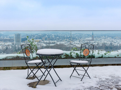 在Schlossberg山上，桌子和椅子上覆盖着雪，在奥地利斯蒂里亚地区格拉茨市的美丽景色，在冬天