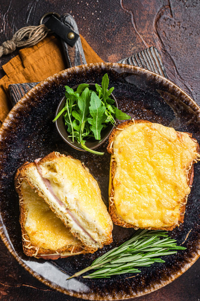 Croque先生烤三明治配奶酪，火腿，格鲁耶尔酱和白汁。黑暗的背景。俯视图
