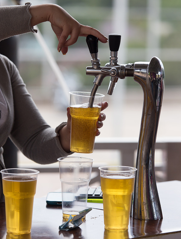 酒保把啤酒倒进塑料玻璃杯