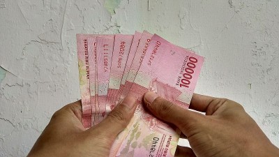 一名男子手里拿着一张10万卢比的钞票