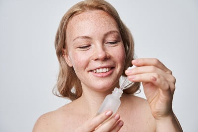 迷人的女人与雀斑的皮肤和裸体化妆在灰色的背景