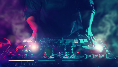 派对夜总会音乐节目主持人(DJ)与电子舞曲混音CD播放器，灯光和烟雾效果在假期