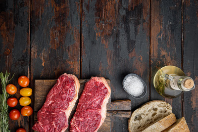 细纹牛排，大理石般的牛肉，在深色木质背景，俯视图，与文本复制空间