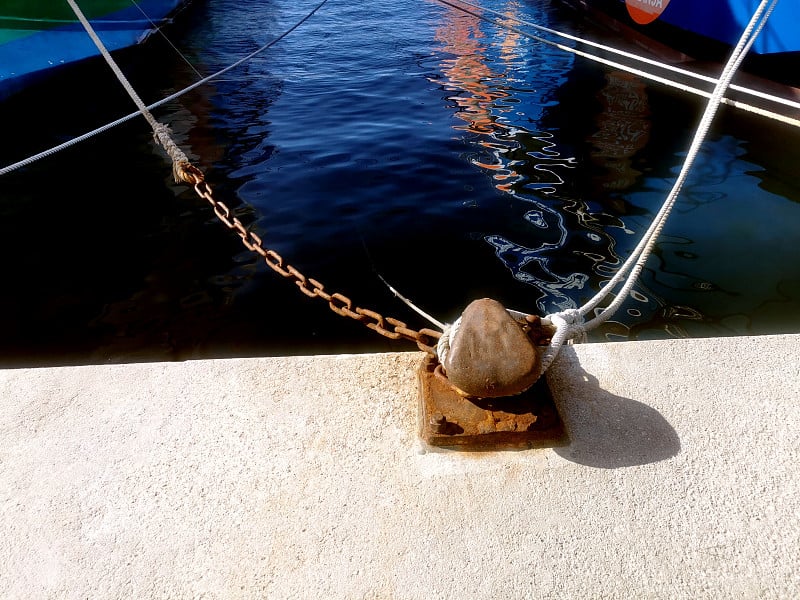 Ship mooring ropes secured around a port bollard