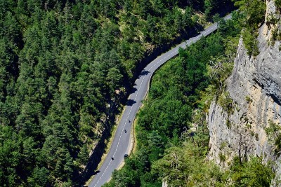三名摩托车手在杜恩峡谷公路上的俯视图，一只狮鹫从他们头顶飞过