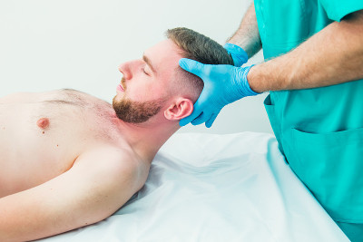 男患者接受治疗师按摩。一个脊椎按摩师在医务室里给病人伸直脖子。神经系统体格检查。整骨疗法、按摩、理疗