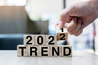 商人手握木制立方体翻转块2021至2022年趋势字在桌子背景。决心，策略，解决方案，目标，业务和新年