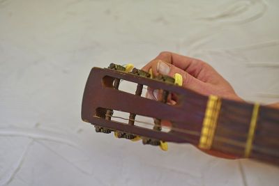 拨动原声吉他主轴箱的调弦杆和齿轮的手指。调优吉他。一个旧的原声吉他的头部细节。副本的空间。