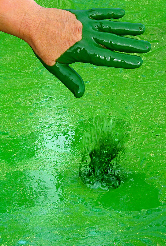 人的手被绿色有害物质和液体飞溅污染。