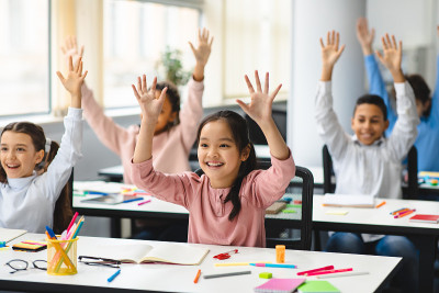 不同的小学生在教室举手