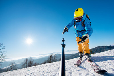 一名男性滑雪者在山里自拍时把相机掉在单脚架上