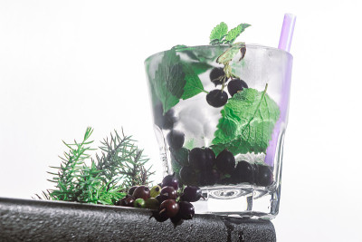 浆果鸡尾酒，薄荷，冰镇在一个酒吧柜台的边缘白色背景。机器人视图，近景，水平方向