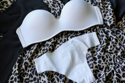 皮肤米色女性内衣:乳罩、内裤和香水躺在动物豹纹衣服的背景上。美丽、时尚的概念。基本的内衣。