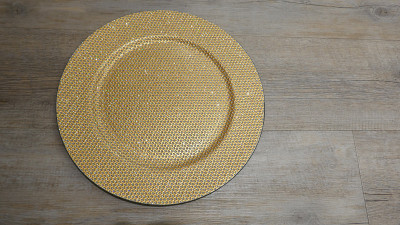 金色闪光的盘子，孤立在木制背景上。前视图。