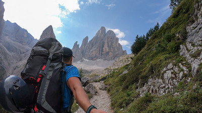 Oberbachernspitze——一名背着大背包的男子在意大利Dolomites地区一条狭窄的小