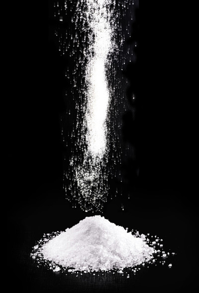 粗盐落下，倒在一堆盐上。黑色背景,孤立