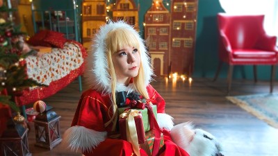 可爱的女孩cosplay圣诞Miku圣诞老人服装和礼物。新年的精灵。坐在地板上