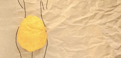 柠檬躺在画好的女性剪影上，在纹理纸的背景上模仿臀部。SPA的概念，身体护理，减肥按摩，抗色素沉着，美