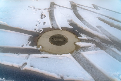在积雪覆盖的道路上的下水道井盖