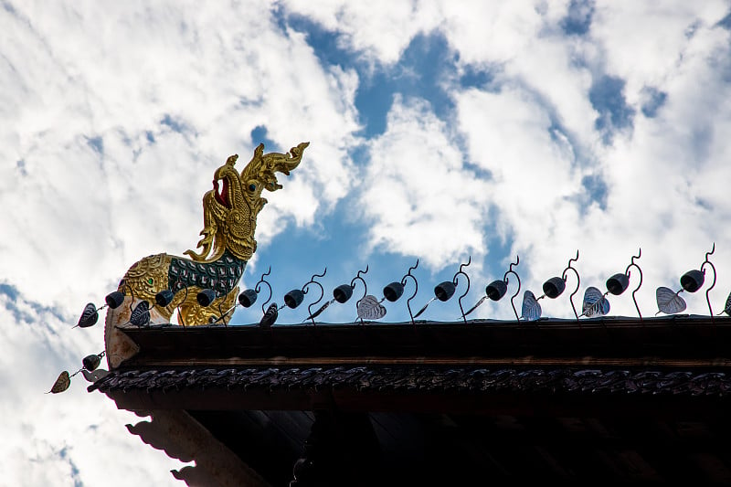 金色的那伽雕塑在佛教寺庙的屋顶，这是泰国建筑装饰装饰与明亮的白色多云的天空。