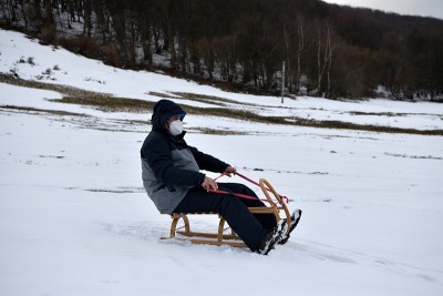 爷爷在冬天的雪地上坐雪橇滑行