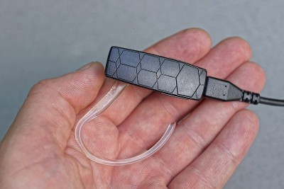 手掌上放着一个大的黑白塑料耳机，上面有一根电线