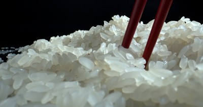 筷子立在一碗黑底白米饭上。白米粒特写。食品的背景。