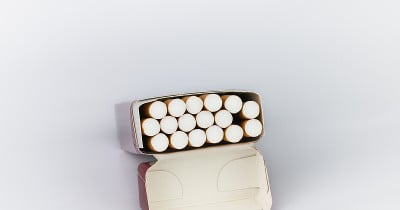许多棕色香烟装在红纸信封里，打开时连同烟盒一起横置在白色背景上