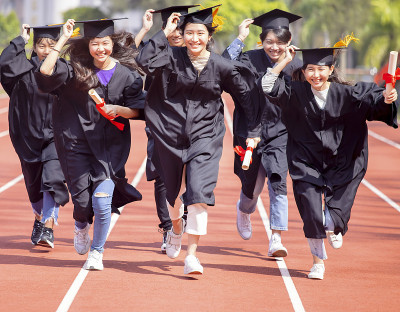 快乐毕业的同学们拿着毕业证书，在学校的体育馆里奔跑