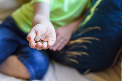 孩子手里拿着钱，现金是英国货币硬币