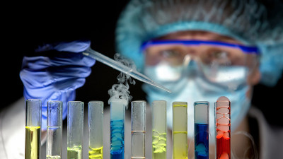 研究人员用吸管将化学液体滴入管中，检查反应