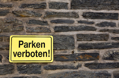 德国黄色“parken verboten”/禁止停车的标志挂在砖墙上。